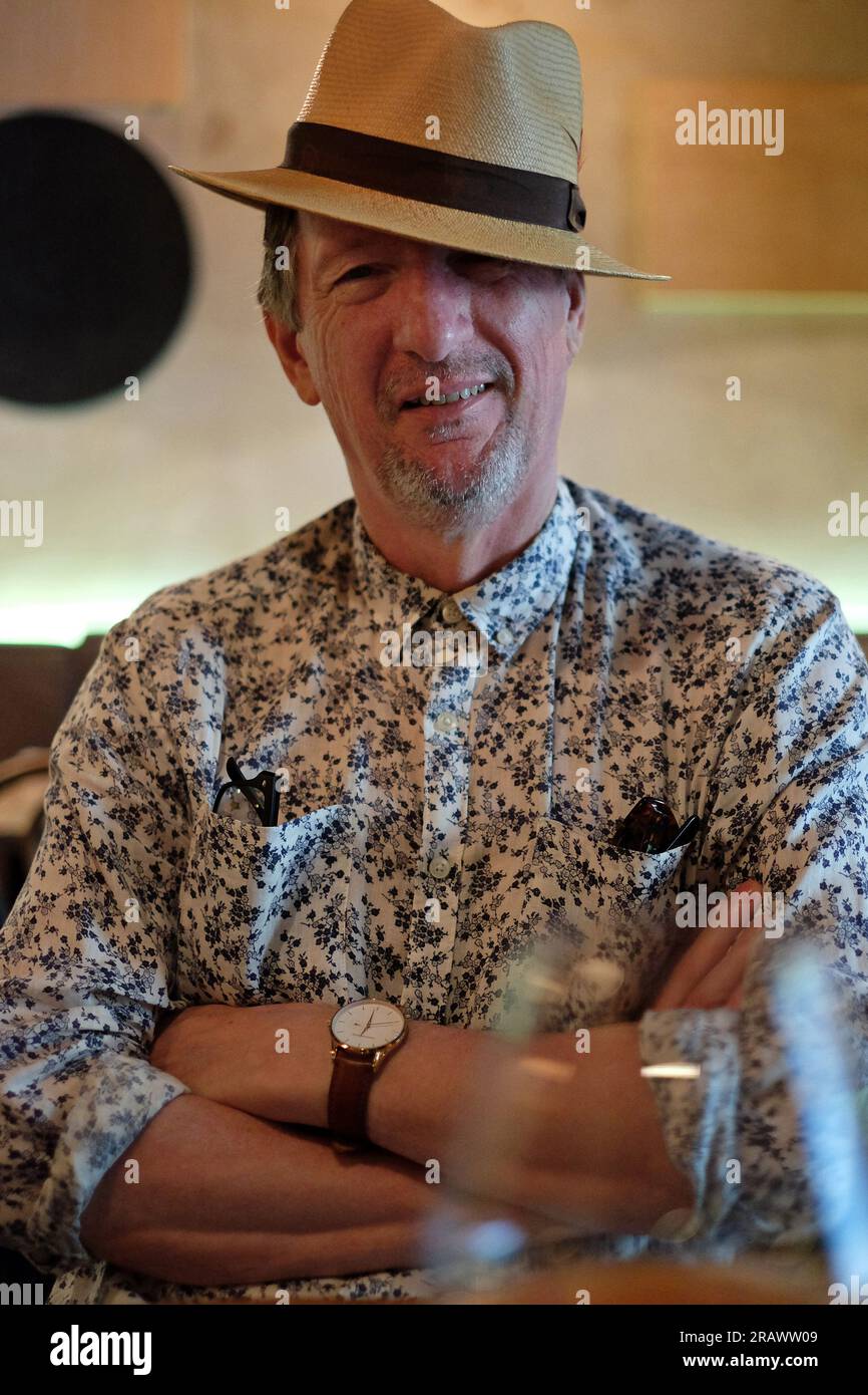 Un uomo felice sorridente con le braccia piegate indossando un cappello Panama al chiuso a pranzo in un ristorante alla moda, Potts Point, Sydney. Foto Stock