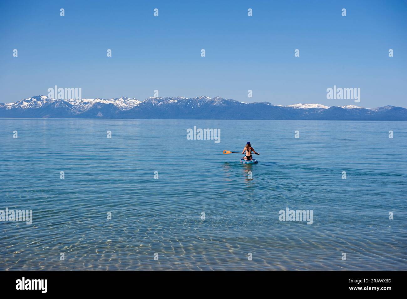 Donna che rema in canoa sulle acque limpide di Tahoe, California Foto Stock