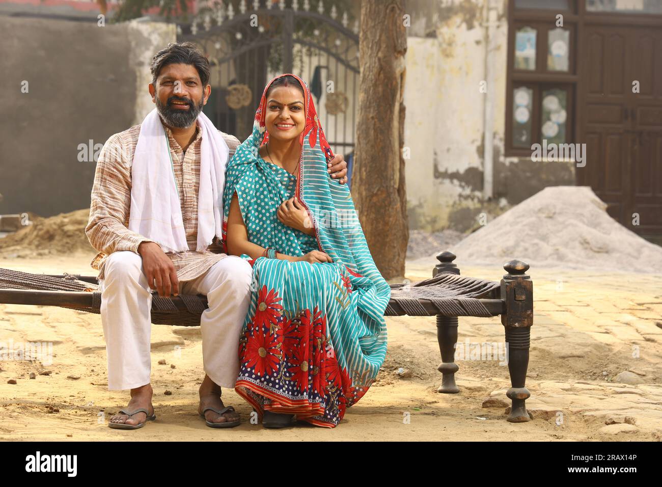 Uomo anziano seduto in ambiente rurale con indosso kurta-pigiama che è un abito tradizionale per gli uomini nel nord dell'India di giorno con sua moglie. Foto Stock