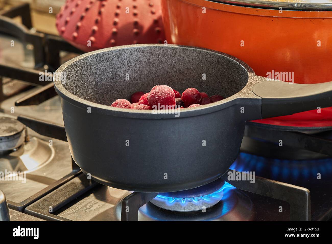 Teglia con frutti di bosco surgelati sul fuoco sulla stufa a gas. Foto Stock