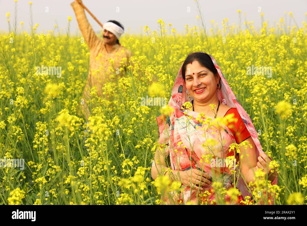 Felice famiglia rurale indiana in piedi in un campo di senape. Sono lieto di vedere i benefici agricoli in termini di guadagni. Foto Stock