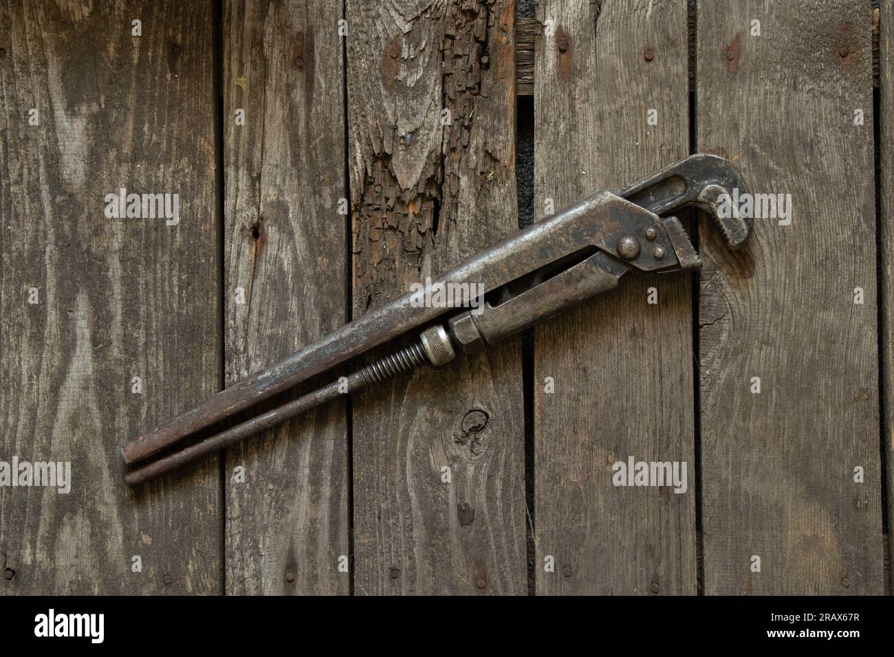 vecchia chiave a gas arrugginita si trova su un tavolo di legno primo piano Foto Stock