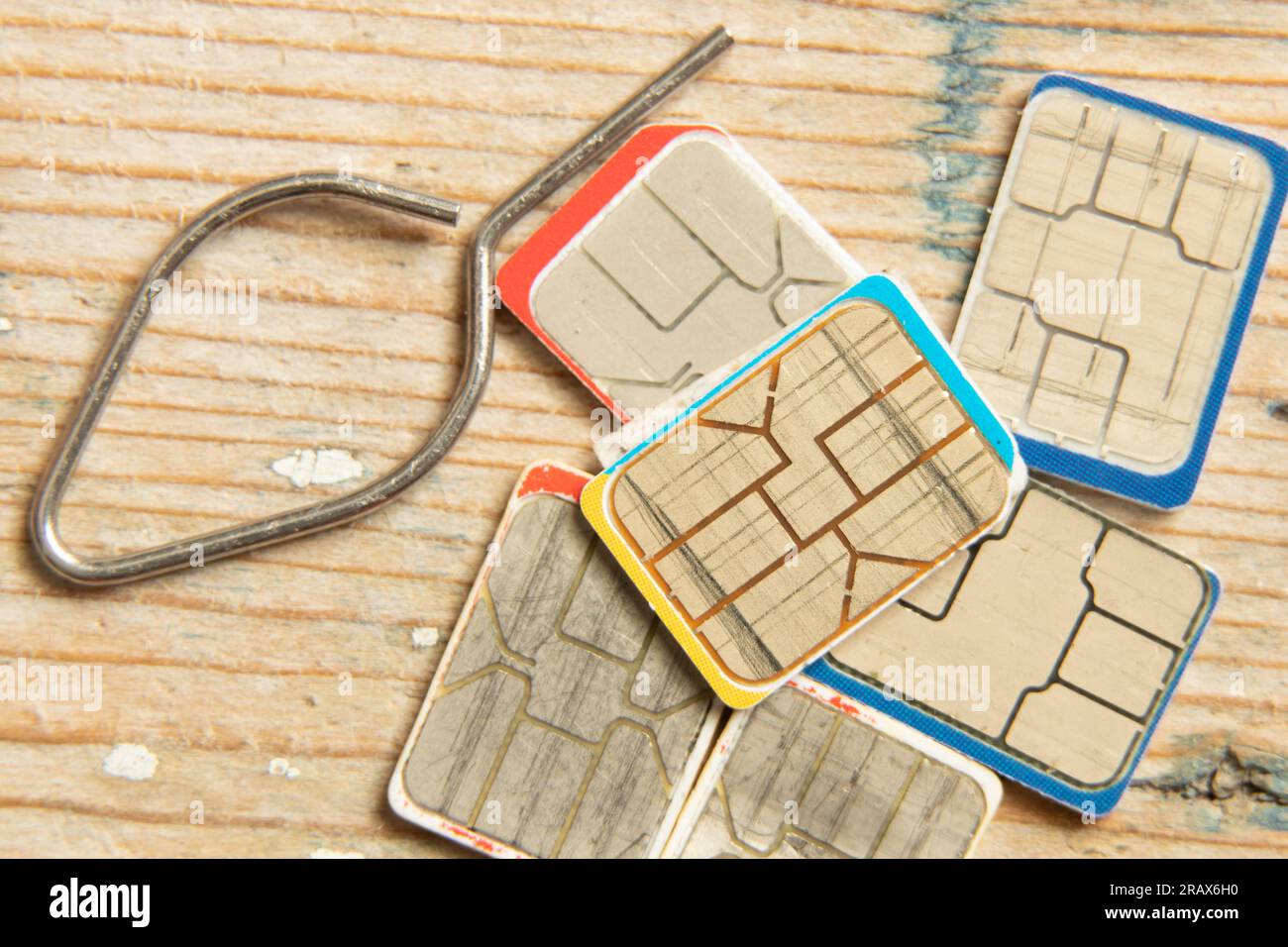 le schede sim e un perno per l'apertura dell'alloggiamento di una scheda sim si trovano su un tavolo di legno Foto Stock