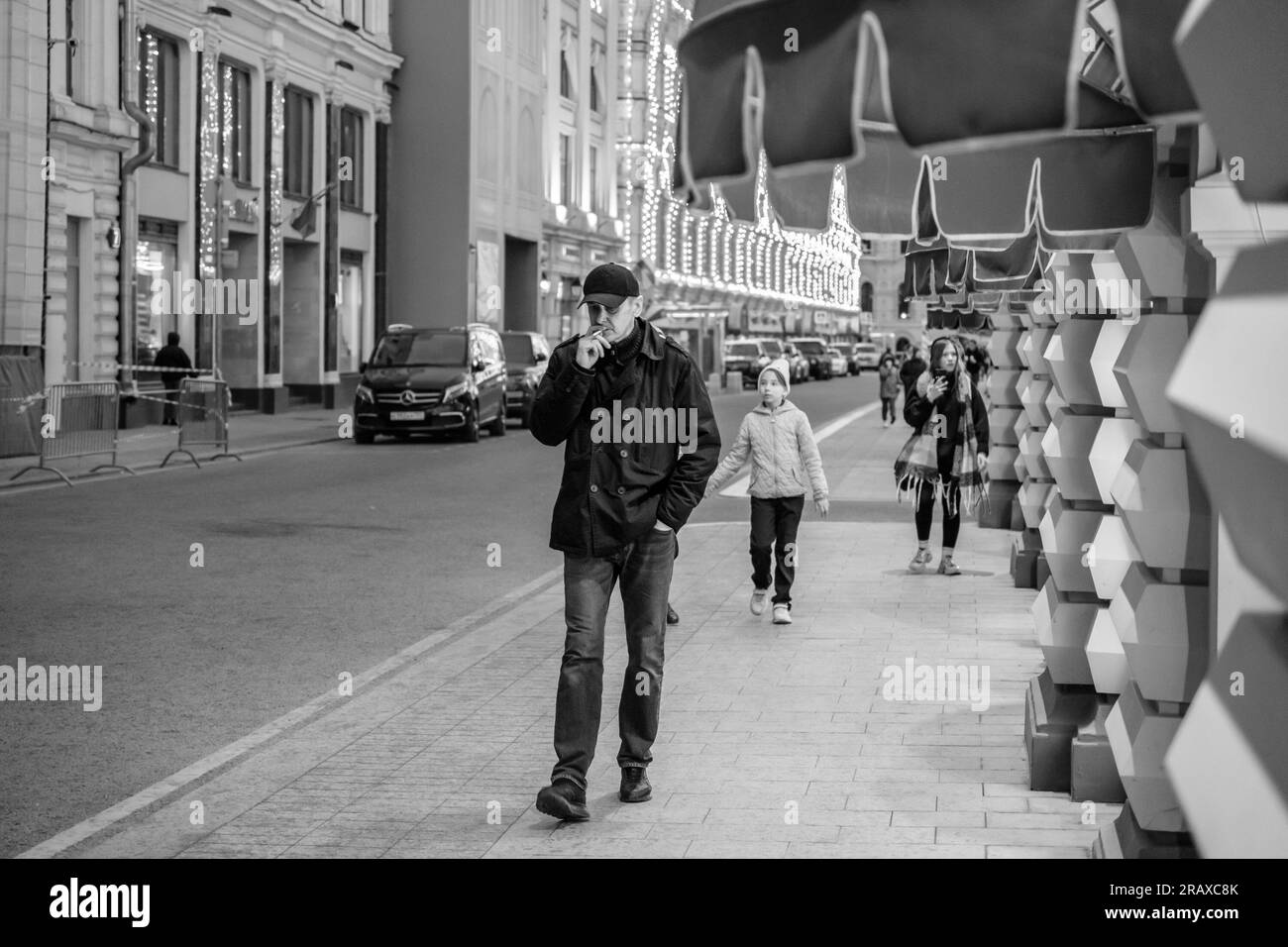 Mosca. Russia. 20 maggio 2023. Un uomo cammina lungo Vetoshny Lane a Mosca passando davanti alle finestre del grande magazzino principale. L'uomo sta fumando. Foto lifestyle. Foto in bianco e nero. Foto Stock