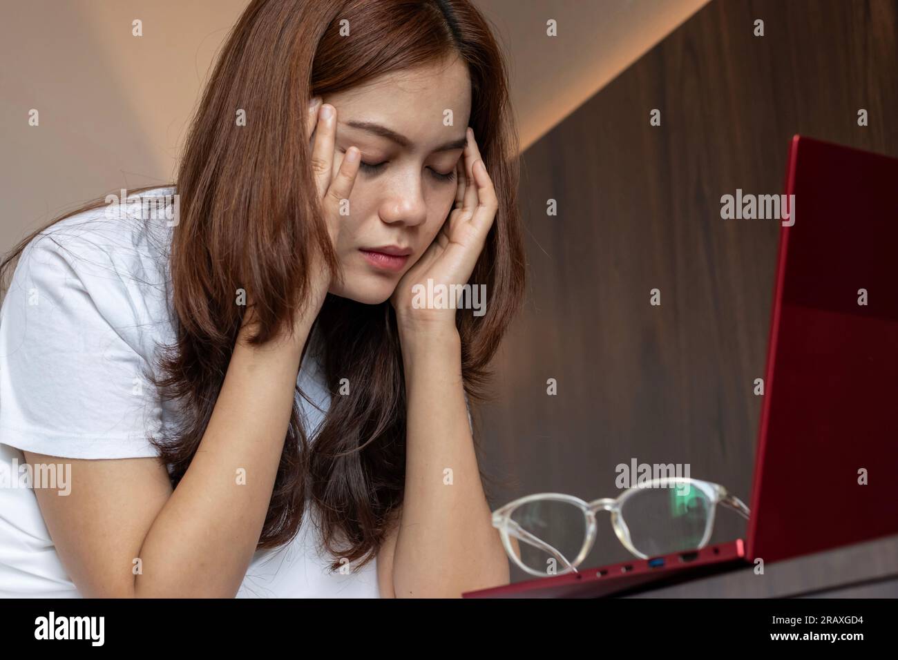 Giovane donna asiatica che messaggia il suo tempio. Concetto di cefalea, emicrania, vertigini, dolore oculare o affaticamento. Foto Stock