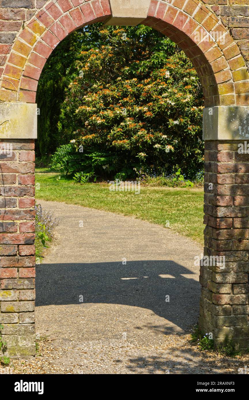 Porta ad arco in un vecchio muro di mattoni in un giardino di campagna inglese. Foto Stock