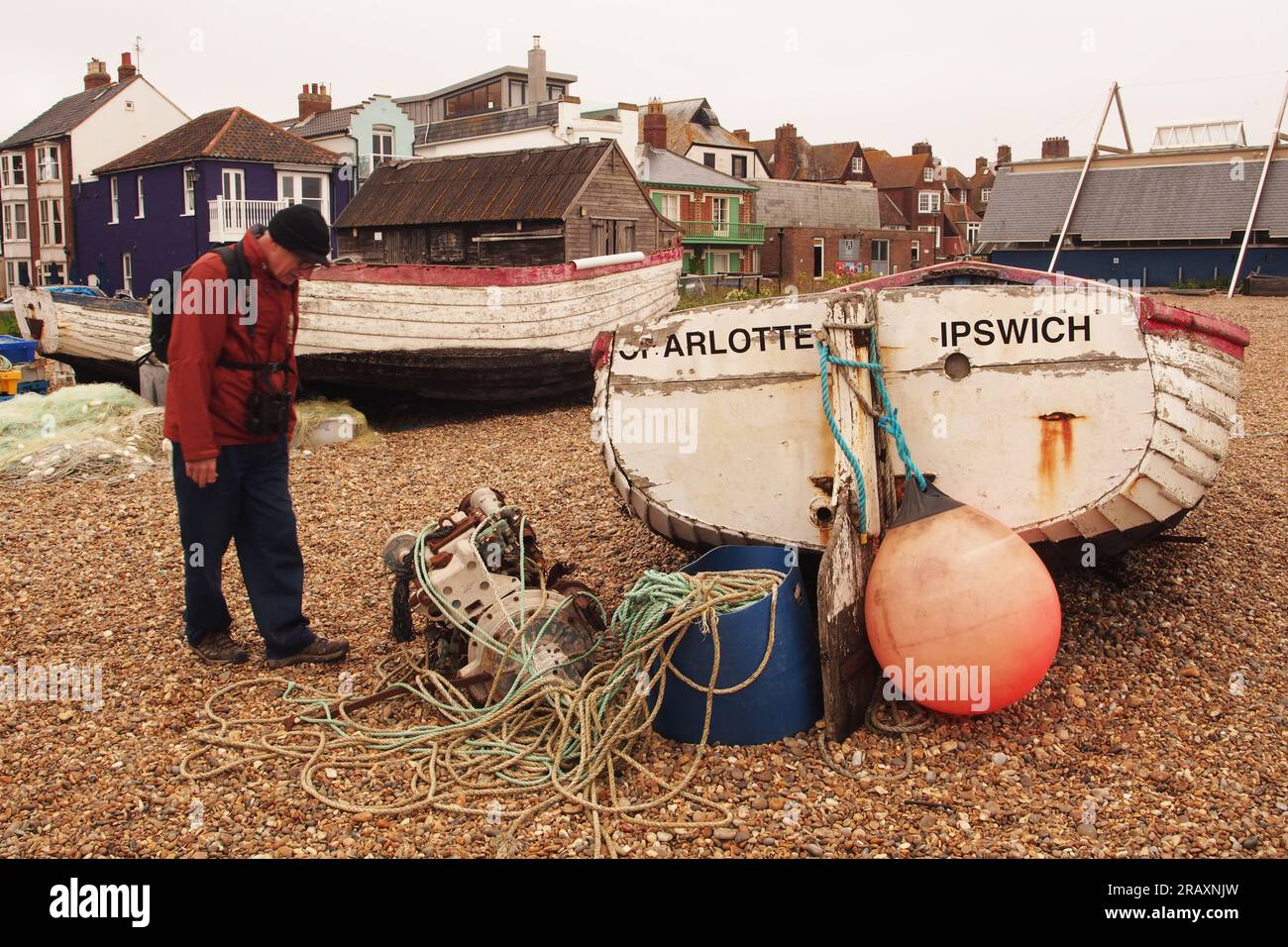 Barca, Charlotte di Ipswich, un motore per barche Lister, corde, una spiaggia di ciottoli, un uomo e proprietà sul mare ad Aldeburgh, Suffolk. REGNO UNITO Foto Stock