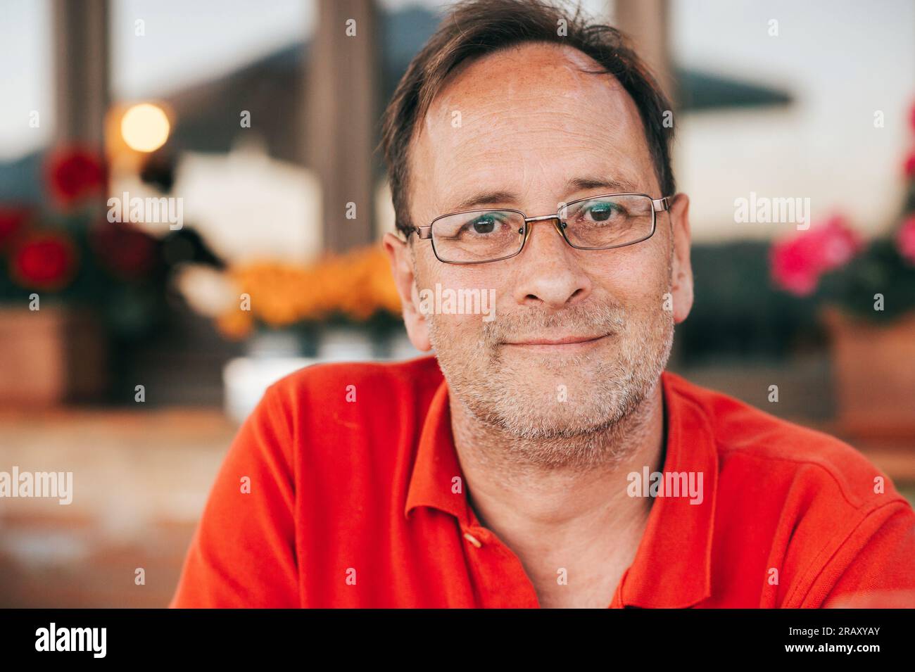Ritratto all'aperto di un uomo di 50 anni che indossa una polo rossa e occhiali da vista Foto Stock