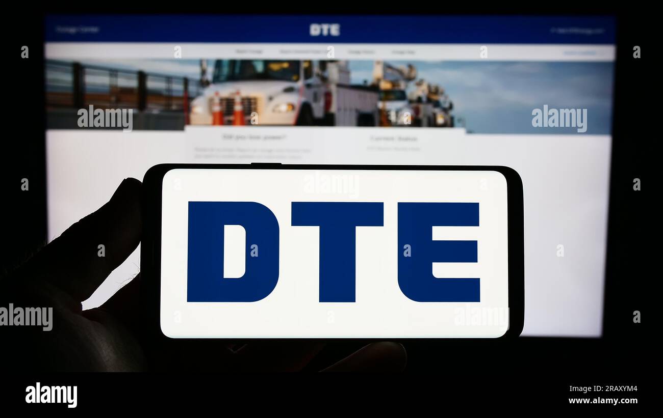 Persona che possiede uno smartphone con il logo della società statunitense DTE Energy Co. Sullo schermo di fronte al sito Web. Concentrarsi sul display del telefono. Foto Stock