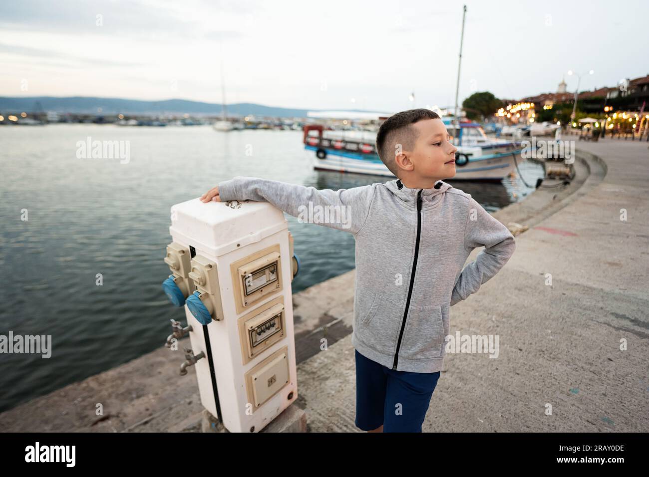 Giovane ragazzo in piedi sul molo vicino al mare. Foto Stock