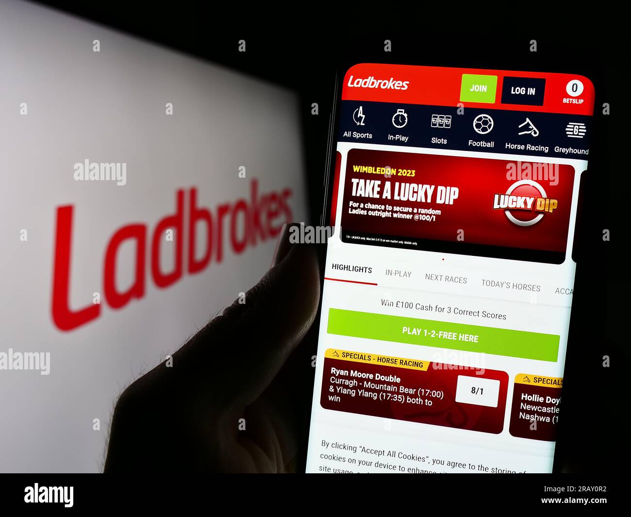Persona che possiede uno smartphone con il sito Web della società LC International Limited (Ladbrokes) sullo schermo con il logo. Concentrarsi sul centro del display del telefono. Foto Stock