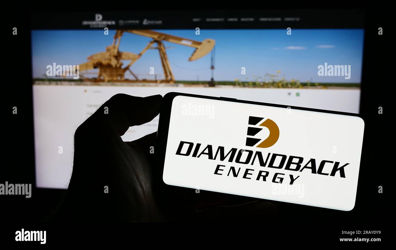 Persona in possesso di un cellulare con il logo della società americana di petrolio e gas Diamondback Energy Inc. Sullo schermo di fronte alla pagina Web. Concentrarsi sul display del telefono. Foto Stock