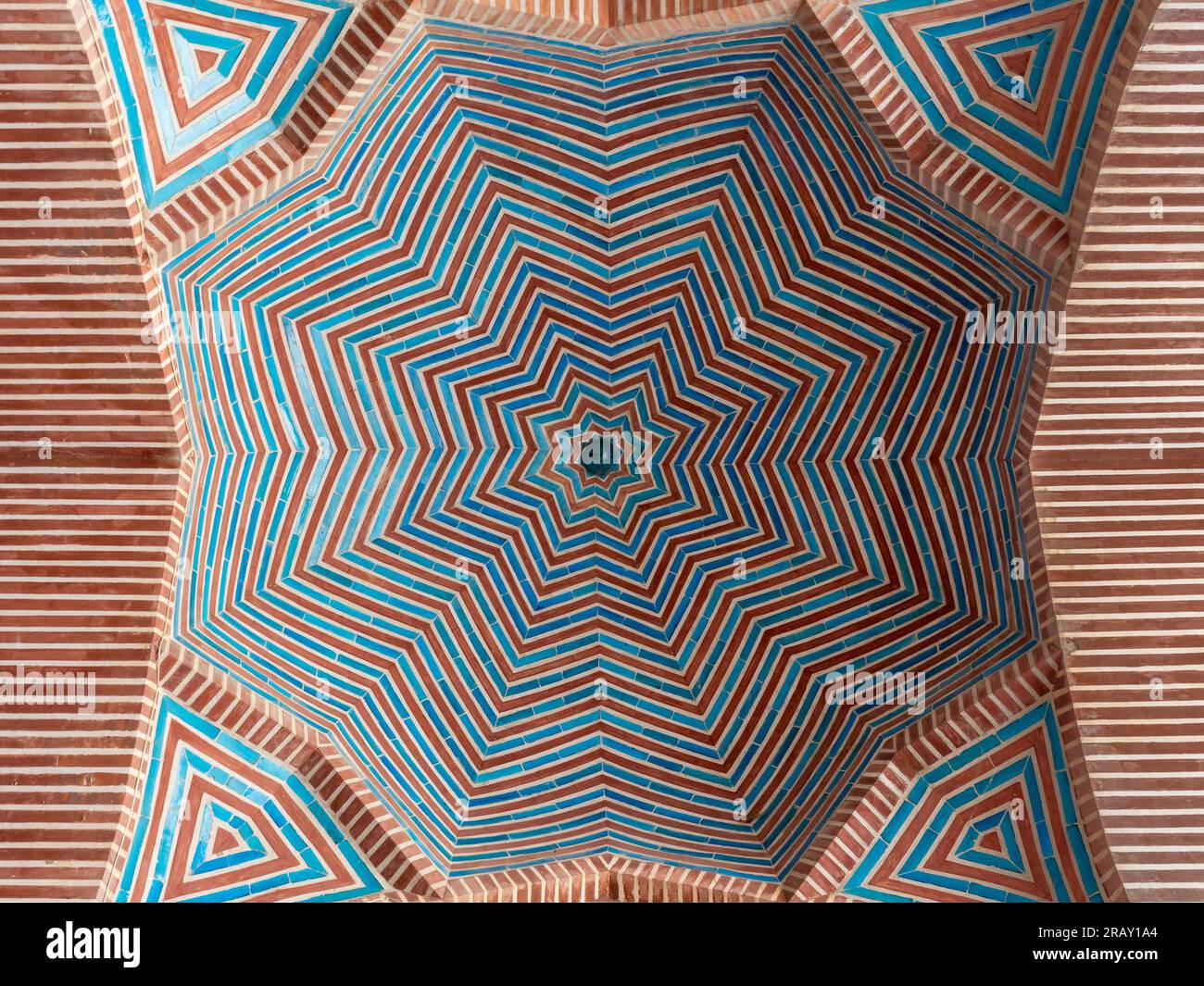 Splendido design geometrico a forma di stella in mattoni rossi e piastrelle blu sulla cupola interna dell'antica moschea Shah Jahan a Thatta, Sindh, Pakistan Foto Stock