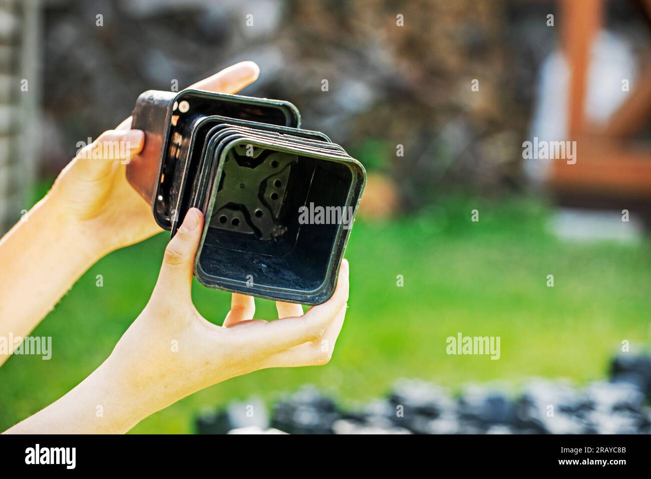 le mani delle ragazze impilano contenitori di plastica vuoti per fiori e piantine. Prenditi cura del giardino e del giardino Foto Stock