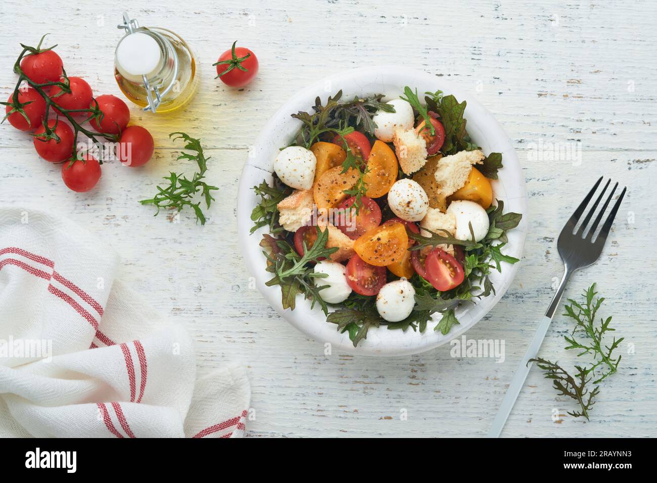 Panzanella toscana. Insalata di pomodori ciliegini con rucola, basilico, mozzarella e cracker di pane su recipiente bianco. Insalata tradizionale italiana. Mediterraneo lui Foto Stock