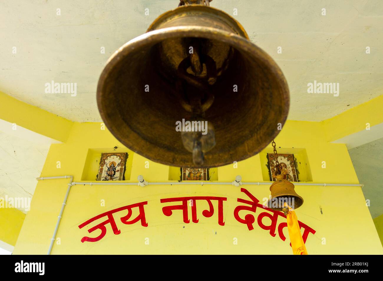 28 giugno 2023, Nagthat, Uttarakhand, India. Grande campana del tempio con la preghiera hindi incisa sullo sfondo. Traduzione inglese del testo, 'Ave Th Foto Stock