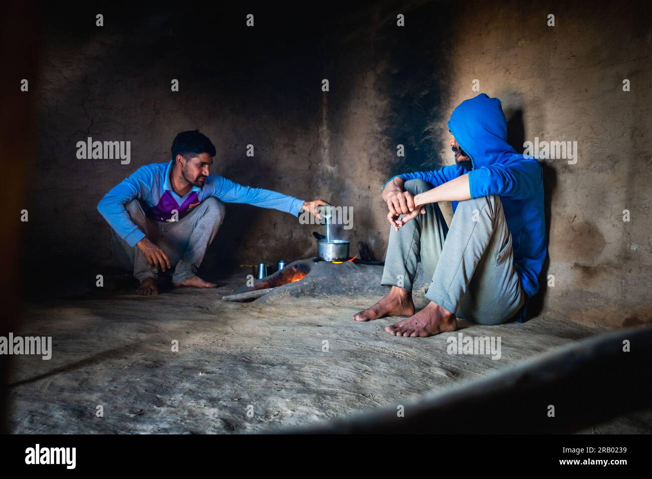 28 giugno 2023, Nagthat, Uttarakhand, India. Due giovani che preparano tè al latte in una stufa di argilla o chulha all'interno di una casa di fango. Soggiorno a casa a Uttarakhand, Foto Stock