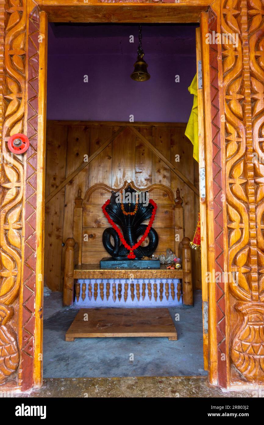 28 giugno 2023, Nagthat, Uttarakhand, India. La divinità indù Nag Devta o il Dio serpente figura in pietra nera in un tempio con un interno in legno. Foto Stock