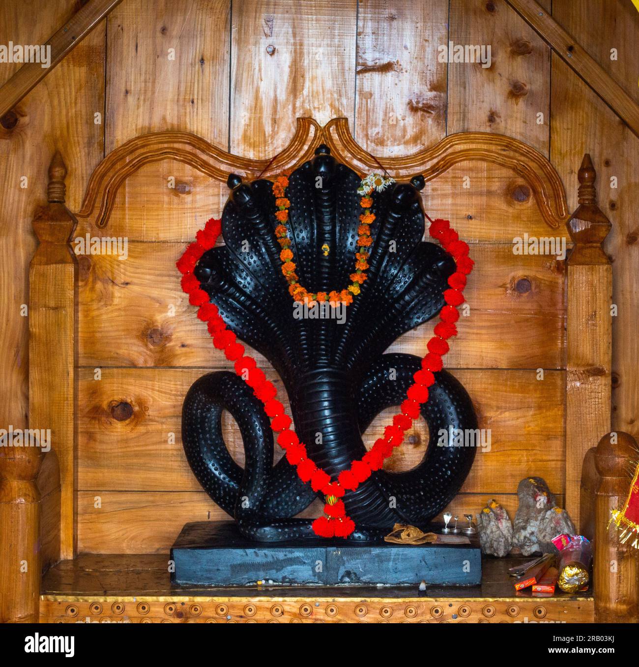 28 giugno 2023, Nagthat, Uttarakhand, India. La divinità indù Nag Devta o il Dio serpente figura in pietra nera in un tempio con un interno in legno. Foto Stock
