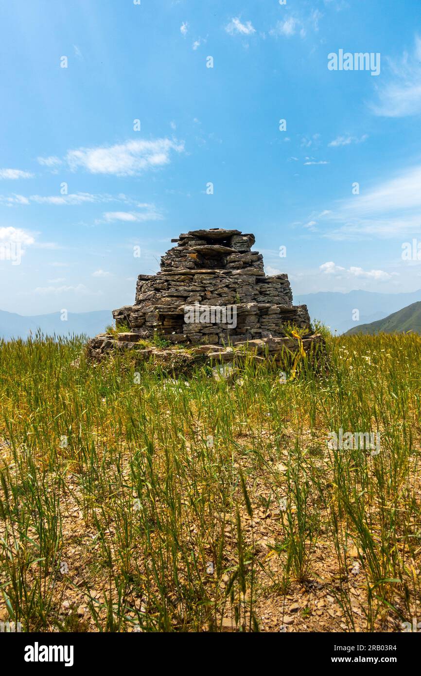 Un'antica piccola piramide a forma di idolo luogo di preghiera fatto di pietre nel mezzo di un prato con splendidi paesaggi. Culture dell'Himalaya Foto Stock