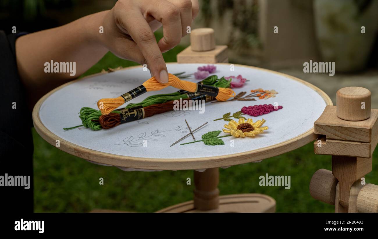 Inizi colorati: Scegliere la lucentezza ricamata per un progetto floreale su tessuto con supporto a cerchio Foto Stock