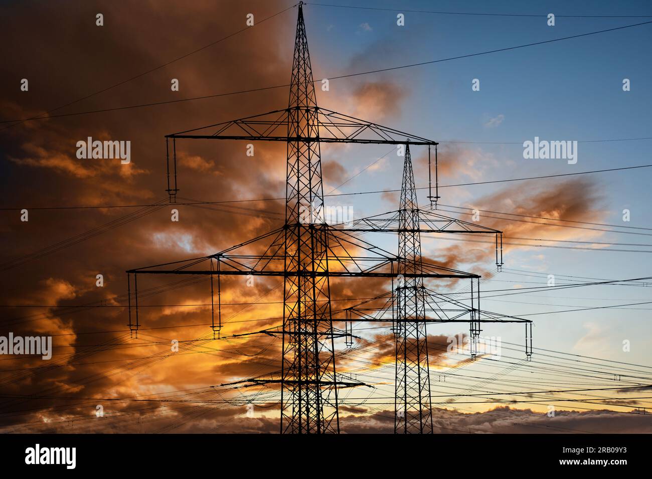 piloni elettrici ad alta tensione contro il cielo con nuvole drammatiche Foto Stock