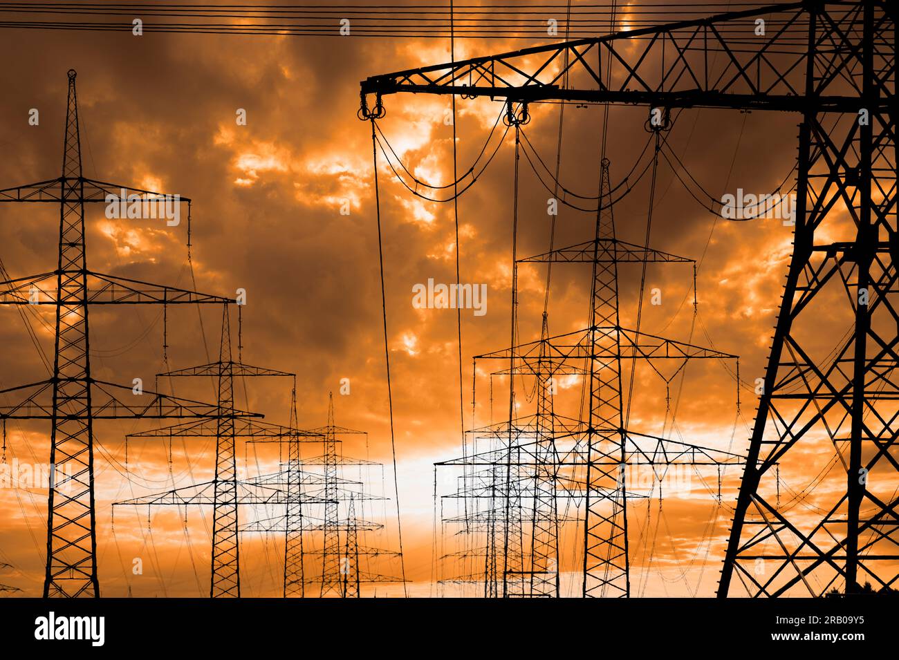 piloni elettrici ad alta tensione contro il cielo con nuvole drammatiche Foto Stock