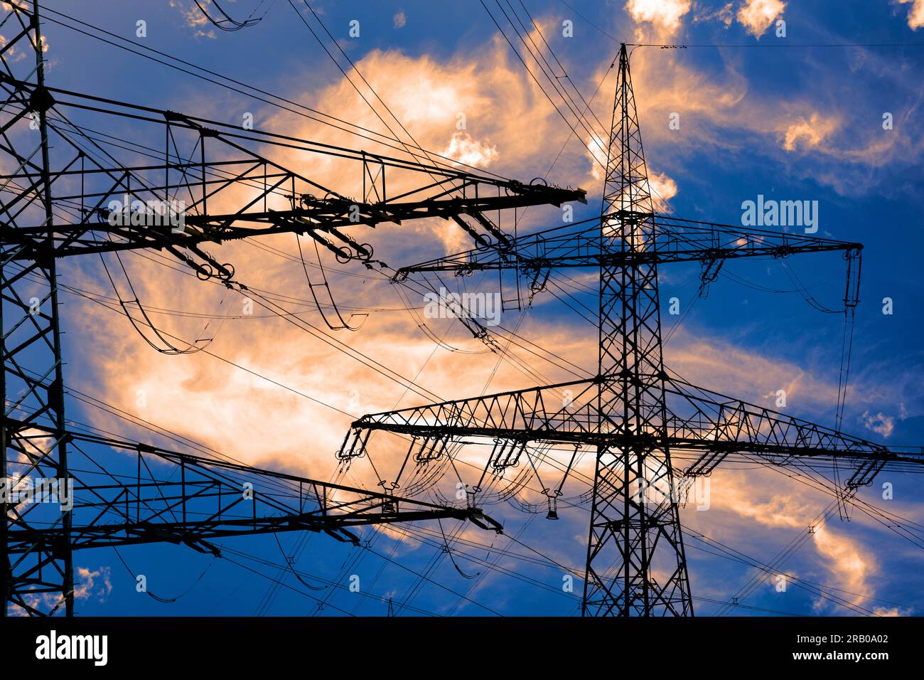 piloni elettrici ad alta tensione contro il cielo con nuvole drammatiche Foto Stock