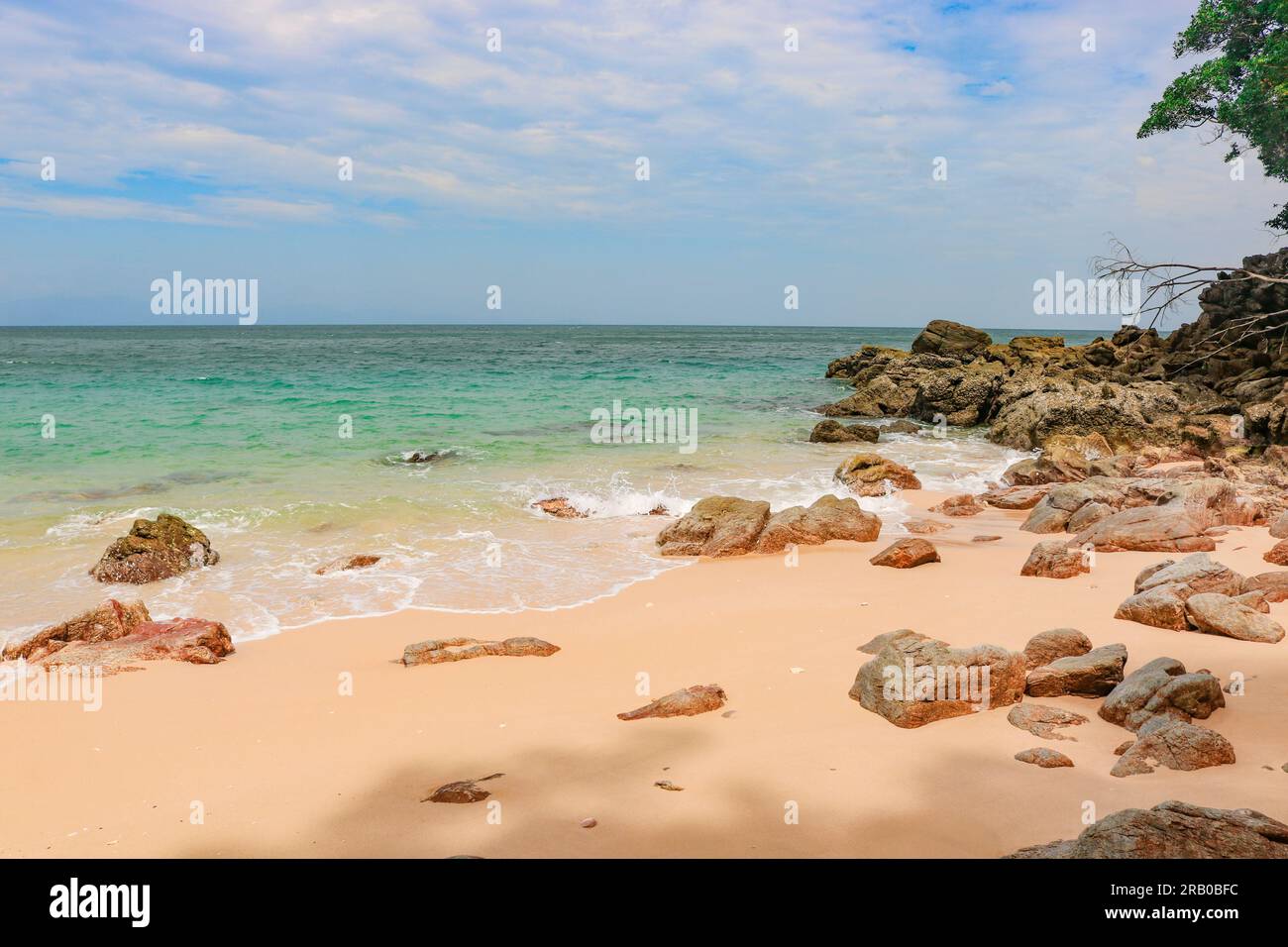 Spiaggia rocciosa di sabbia tropicale con acque cristalline Foto Stock