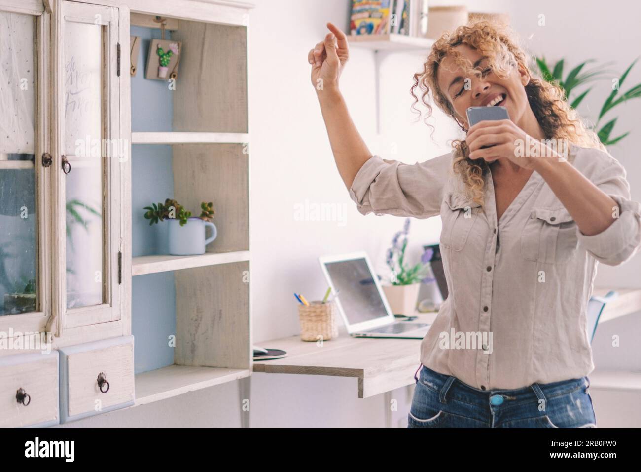 Gioia e stile di vita giovanile eccitata donna che balla e canta a casa per la felicità. Successo e stile di vita sano persone in attività di svago indoor da sole divertendosi con musica e danza. Gioioso Foto Stock