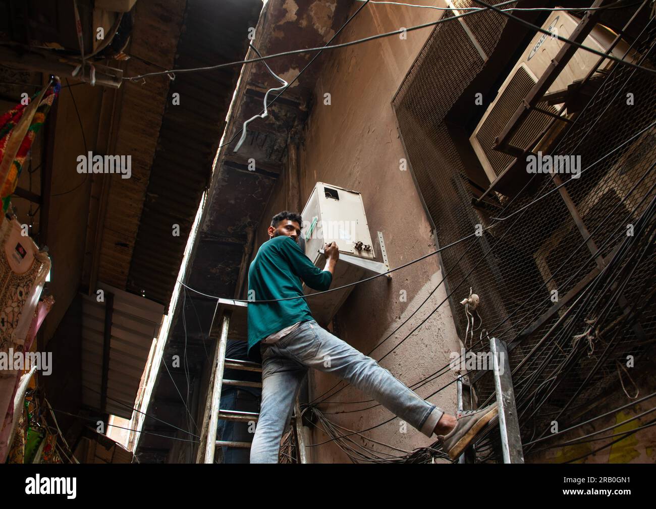 Uomo indiano che installa condizionatori d'aria nella vecchia Delhi, Delhi, nuova Delhi, India Foto Stock