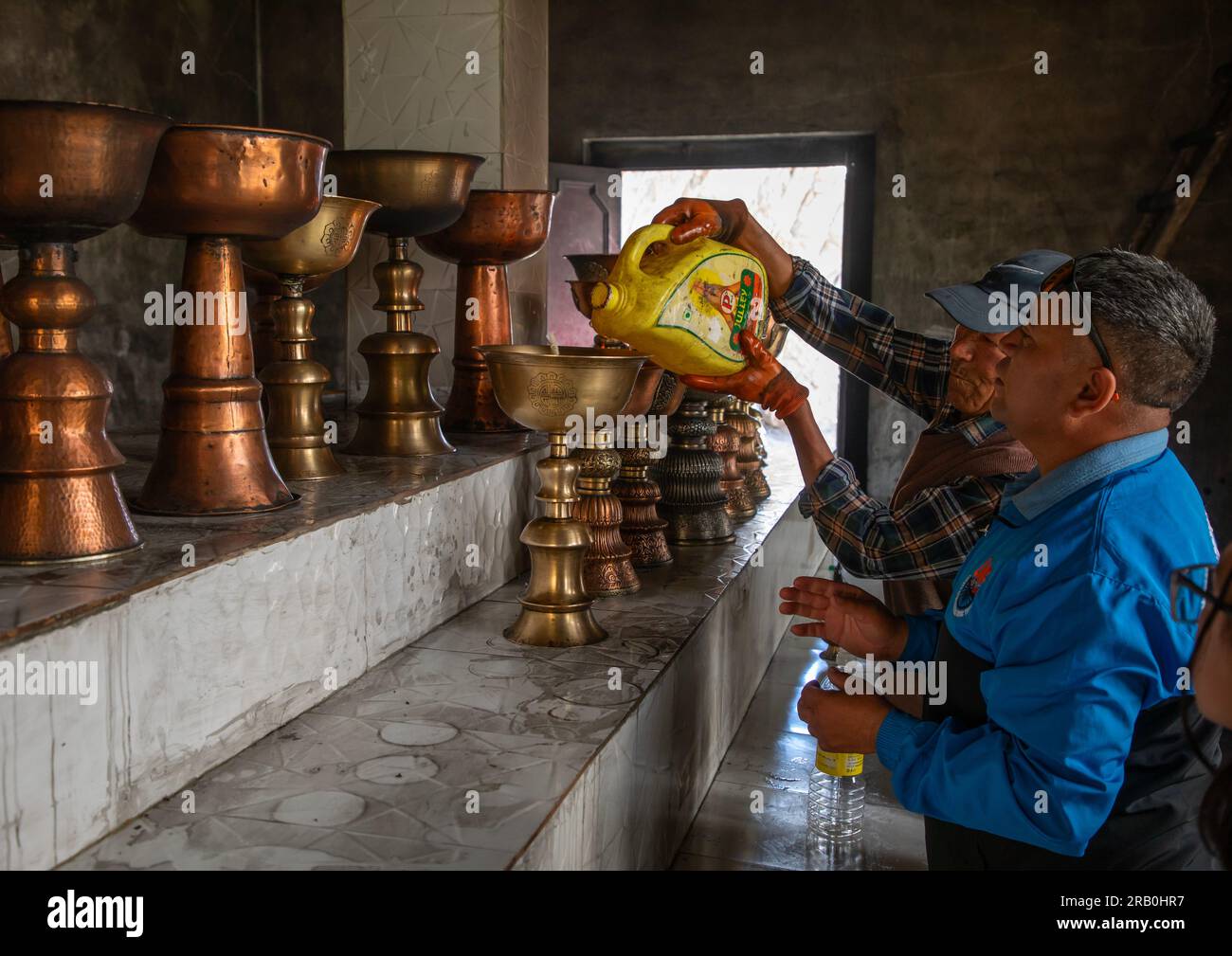 Pellegrini che mettono olio nelle lmaps del petrolio nel monastero di Shey, Ladakh, Shey, India Foto Stock