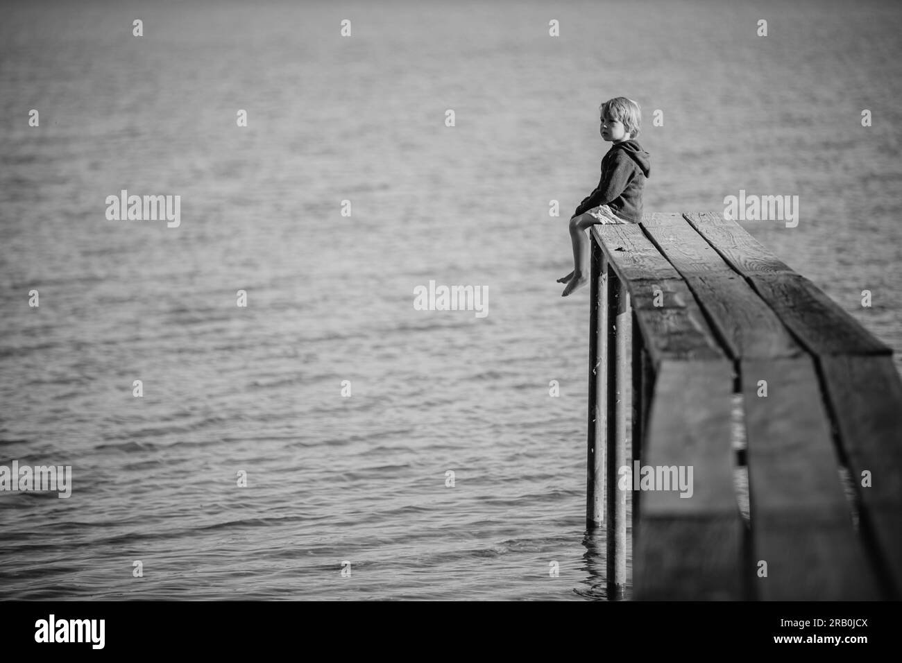 Bambino su un molo vicino al lago Foto Stock