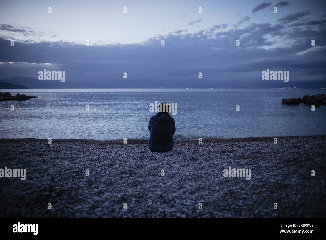 Donna seduta sulla spiaggia, isola di Krk, Croazia Foto Stock