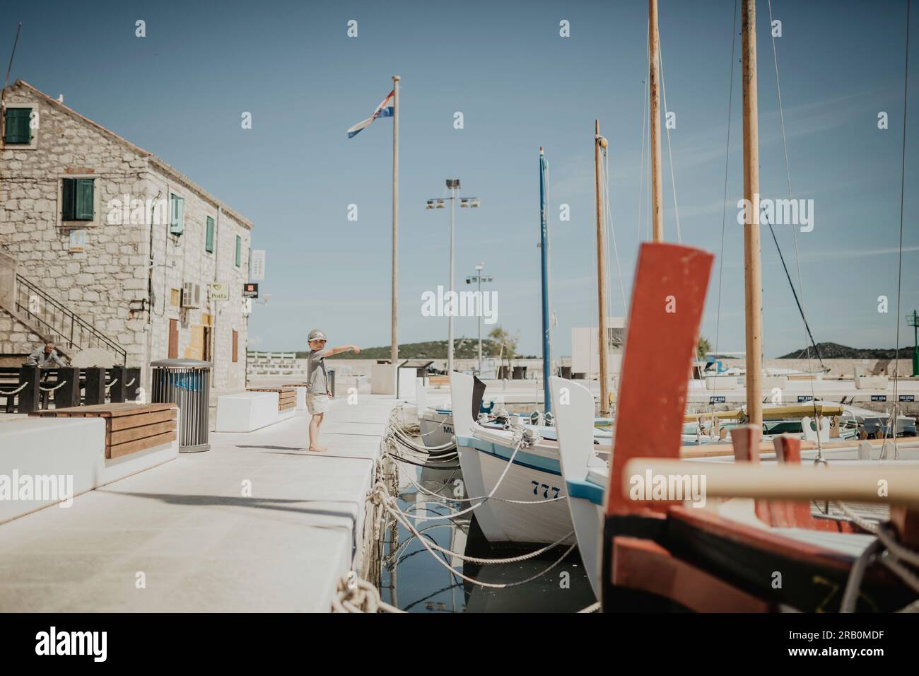 Ragazzo in piedi sul lungomare in un porto, isola di Krk, Croazia Foto Stock