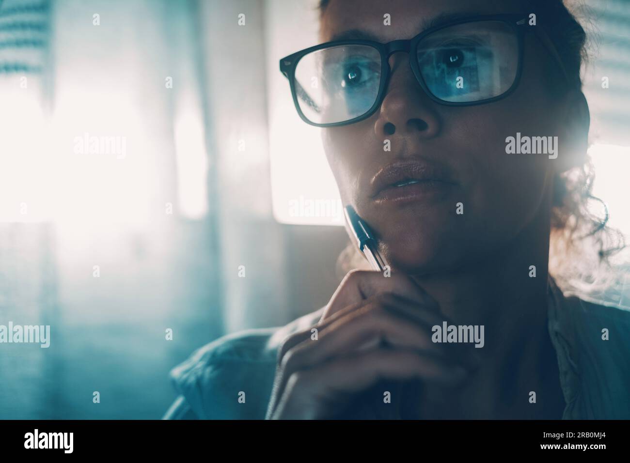 Ritratto di una imprenditrice di tecnologia moderna che pensa al chiuso e indossa occhiali con luce blu e riflessi. Concetto di lavoro moderno e di persone. Espressione femminile premurosa. Blue Mood Foto Stock