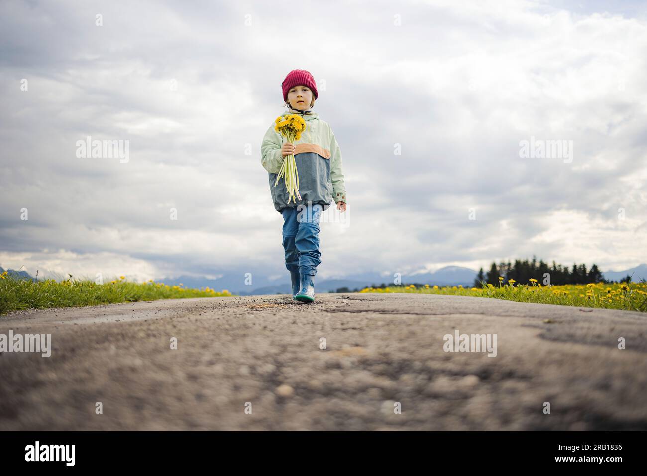 Il ragazzo con il bouquet di fiori cammina lungo una strada sterrata Foto Stock