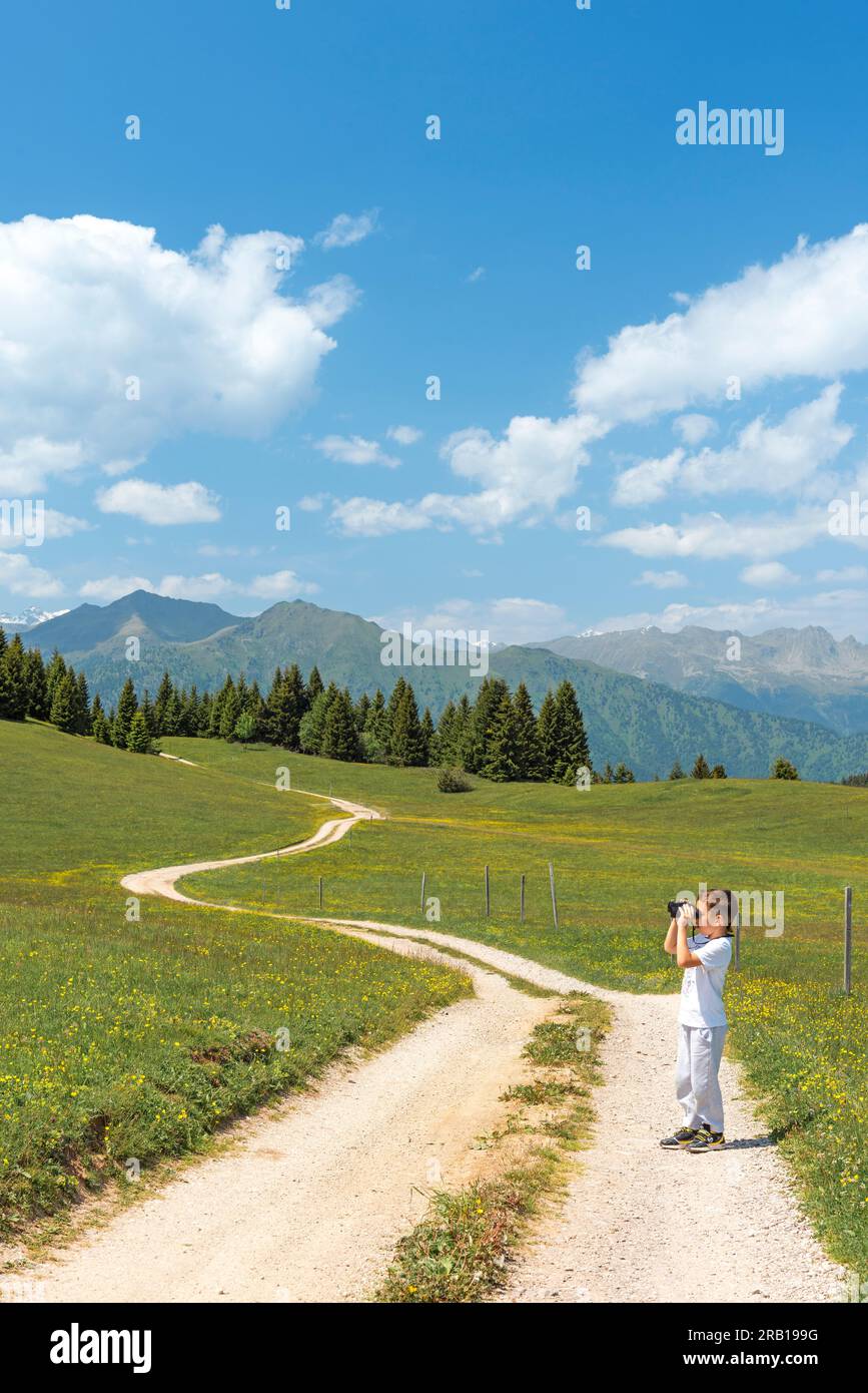 Bambino che guarda le montagne con ammirazione. Europa, Italia, Trentino alto Adige, distretto di Trento, Cles Foto Stock