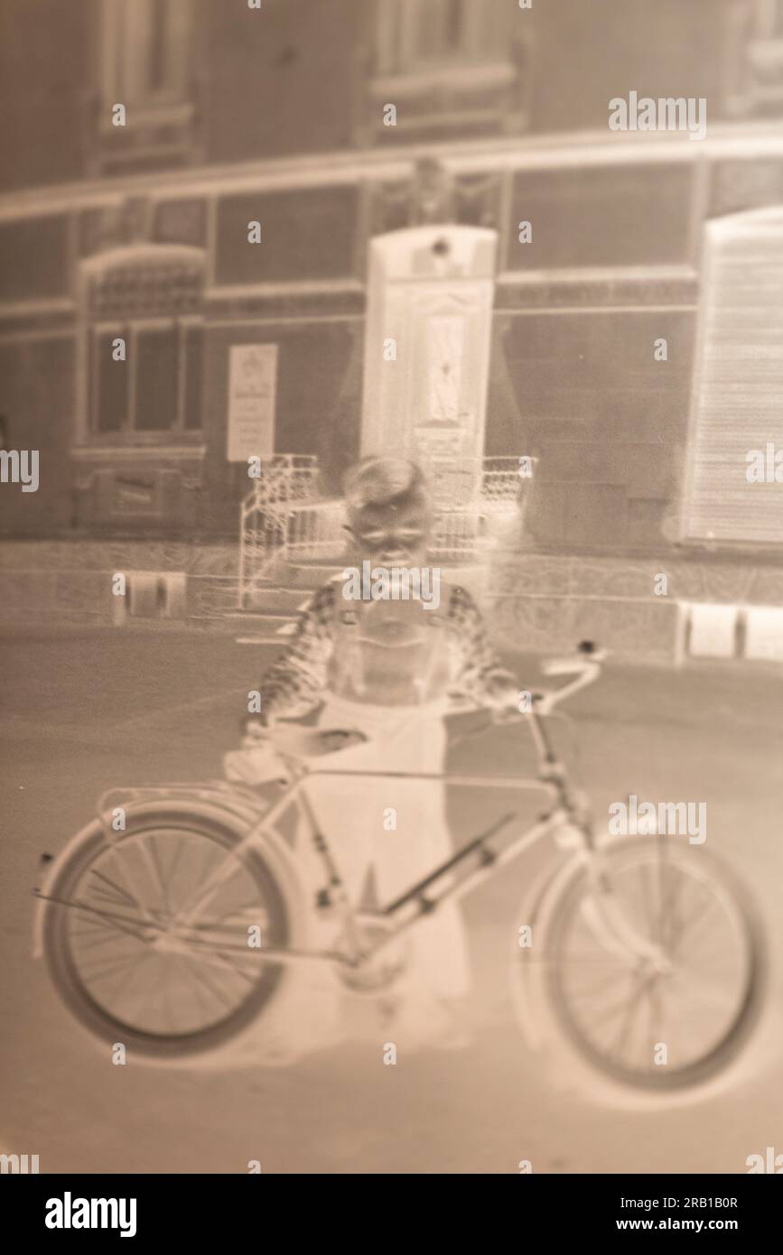 Immagine negativa di un ragazzo con la sua bici davanti al vecchio edificio Foto Stock