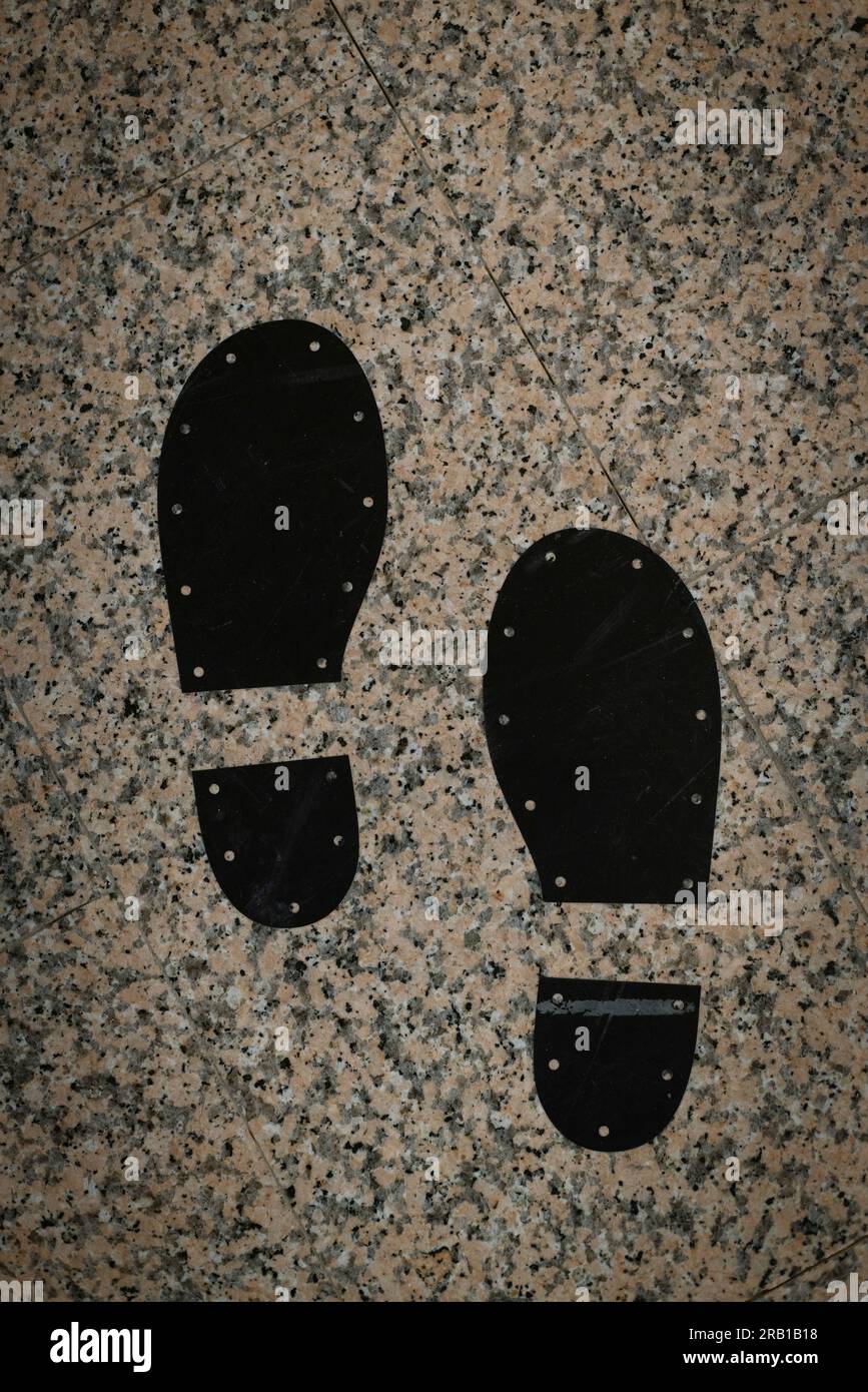 Due impronte nere di scarpe maschili su pavimento piastrellato Foto Stock