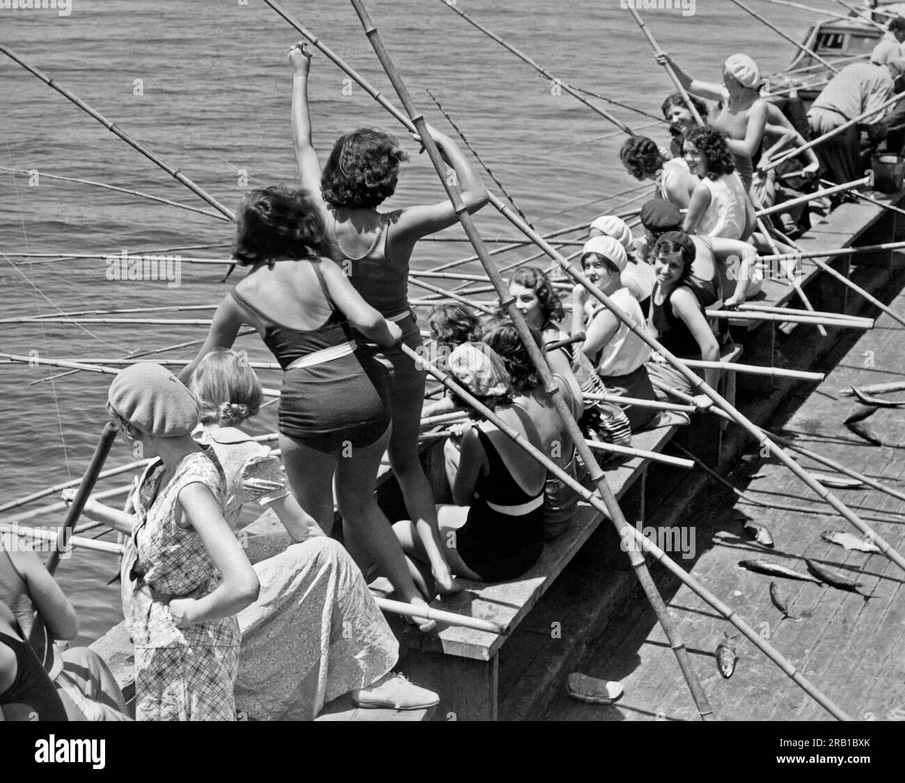 Long Beach, California: c. 1933. Giovani donne che si godono un pomeriggio di pesca con pali di bambù sulla chiatta da pesca. Foto Stock