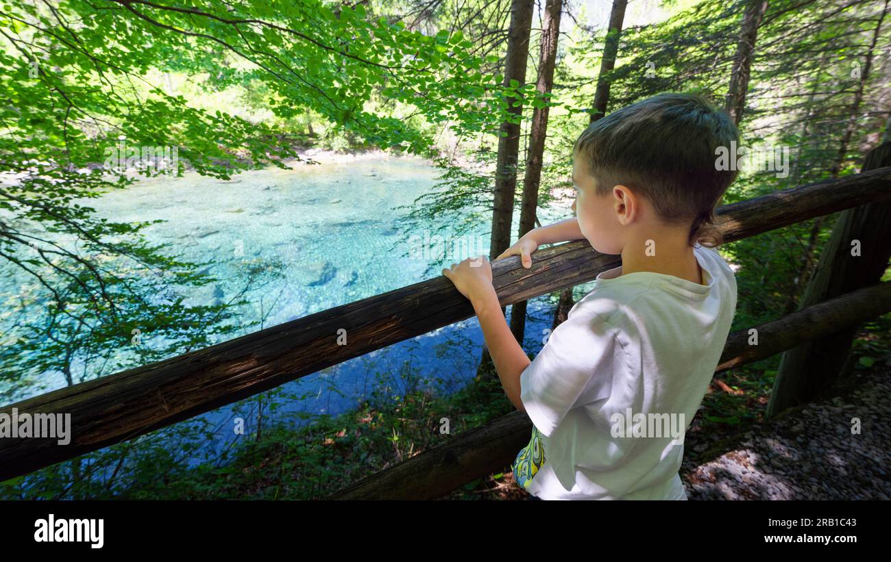 Bambino felice che guarda i colori di questo piccolo lago alpino. Europa, Italia, Trentino alto Adige, provincia di Trento, Ville d'Anaunia Foto Stock