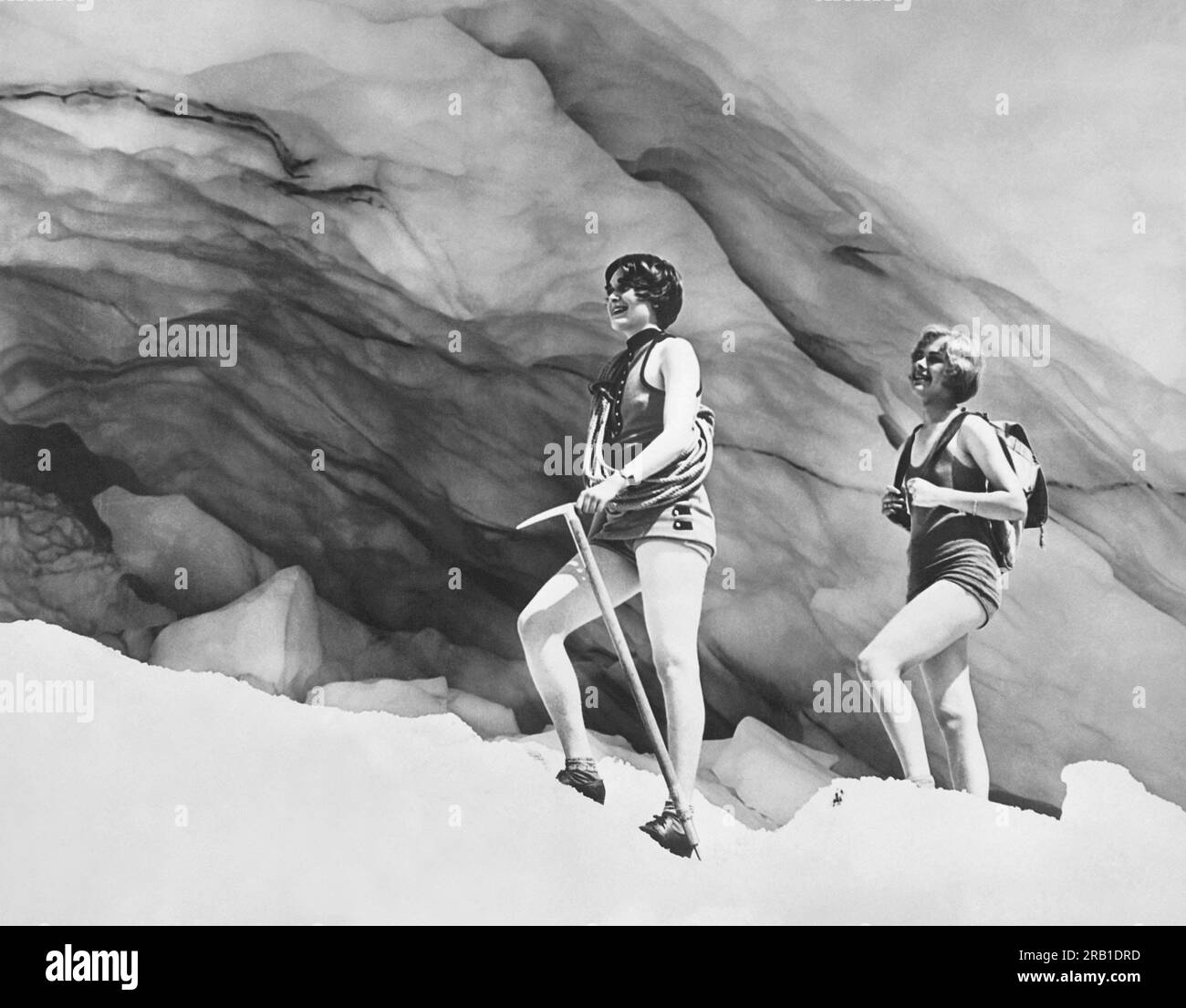 Mount Rainier National Park, Washington: c. 1928 due giovani donne in costume da bagno e attrezzatura da arrampicata si dirigono verso una grotta di ghiaccio sotto il ghiacciaio Paradise. Foto Stock