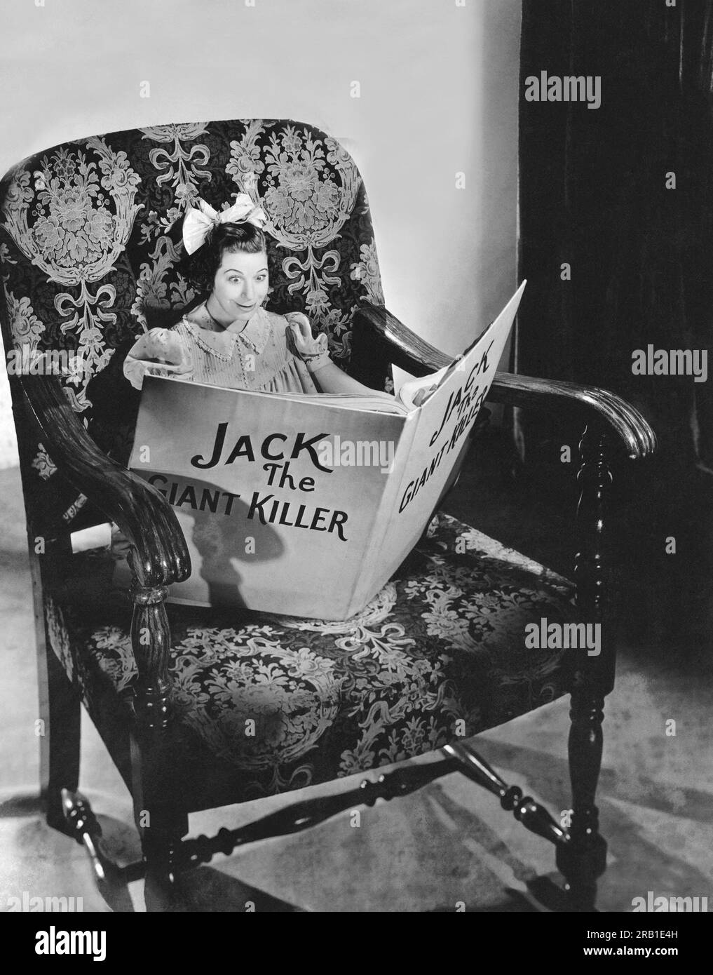 Hollywood, California: 1938 l'attrice Fanny Brice legge un libro su una sedia oversize nel suo ruolo di Baby Snooks nel programma radiofonico "Good News". Foto Stock