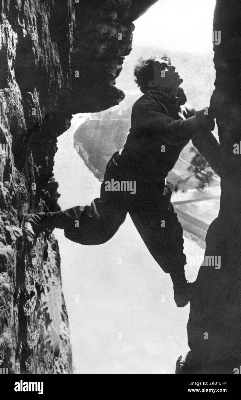 Alpi: c. 1917 stuntman italiano Luciano Albertini che sale su uno stretto crepaccio delle Alpi. Foto Stock