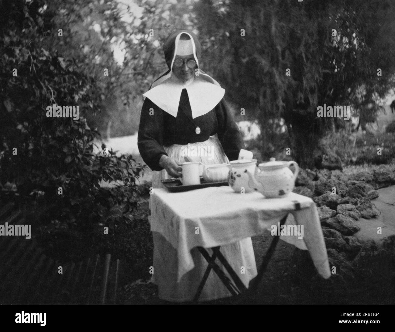 Haifa, Palestina: c. 1930 Una suora cattolica tedesca all'Hospice tedesco che prepara un ambiente per il tè all'aperto. Foto Stock
