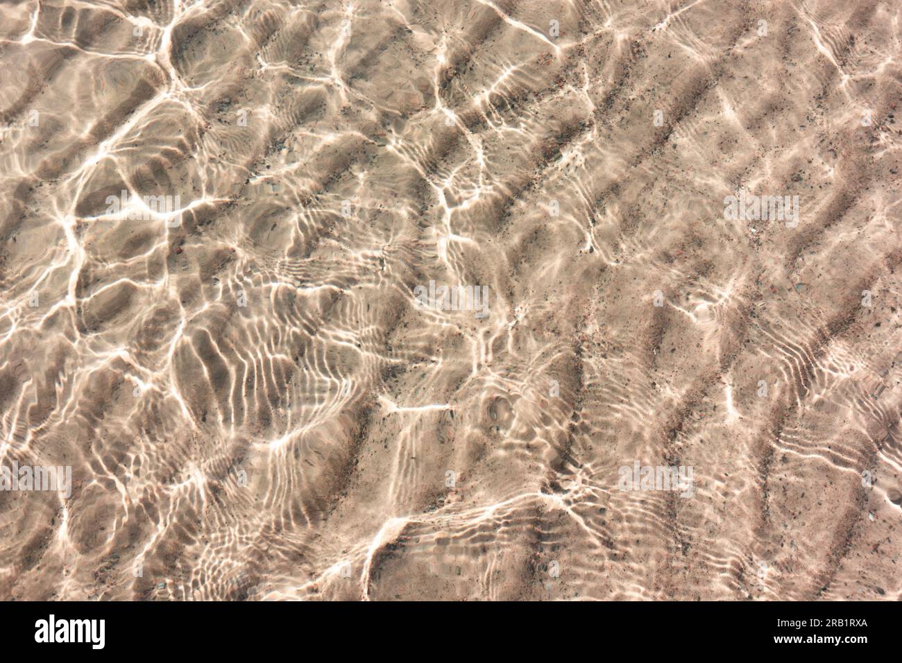 Modello di sabbia bianca sotto l'acqua limpida e trasparente con riflessi del sole in piccole onde dalla spiaggia paradisiaca Foto Stock