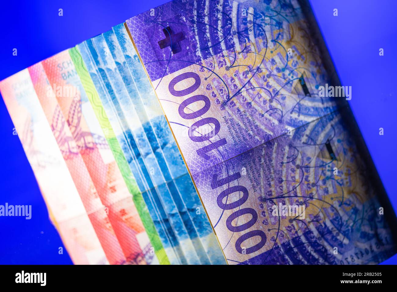 Primo piano colorato delle banconote in franchi svizzeri su sfondo blu. Valuta nazionale Svizzera e Liechtenstein. Foto Stock