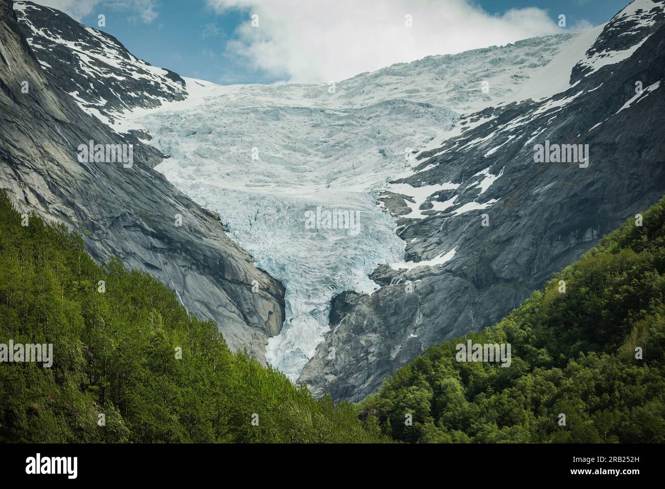 Paesaggio montano panoramico della contea di Vestland in Norvegia. Montagne Rocciose ricoperte di neve e circondate dalla fitta Foresta Verde. Foto Stock