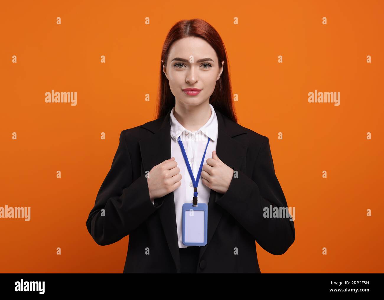 Giovane donna con badge vip Pass su sfondo arancione Foto Stock Giovane donna con badge vip Pass su sfondo arancione Foto Stock